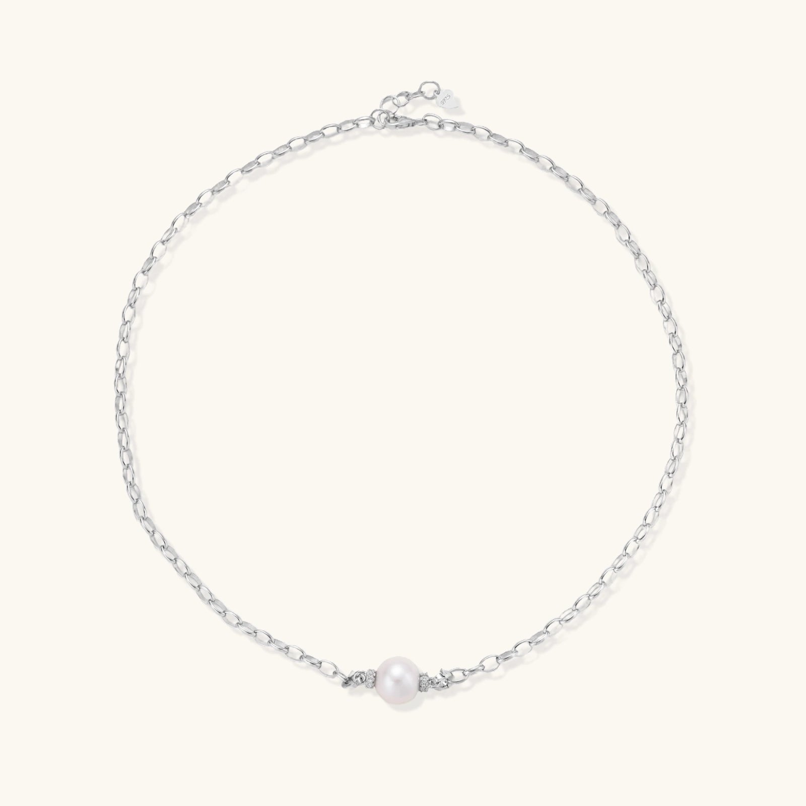 Dainty rhodium-plated silver chain necklace with centered 10mm freshwater pearl and crystal accents on cream background