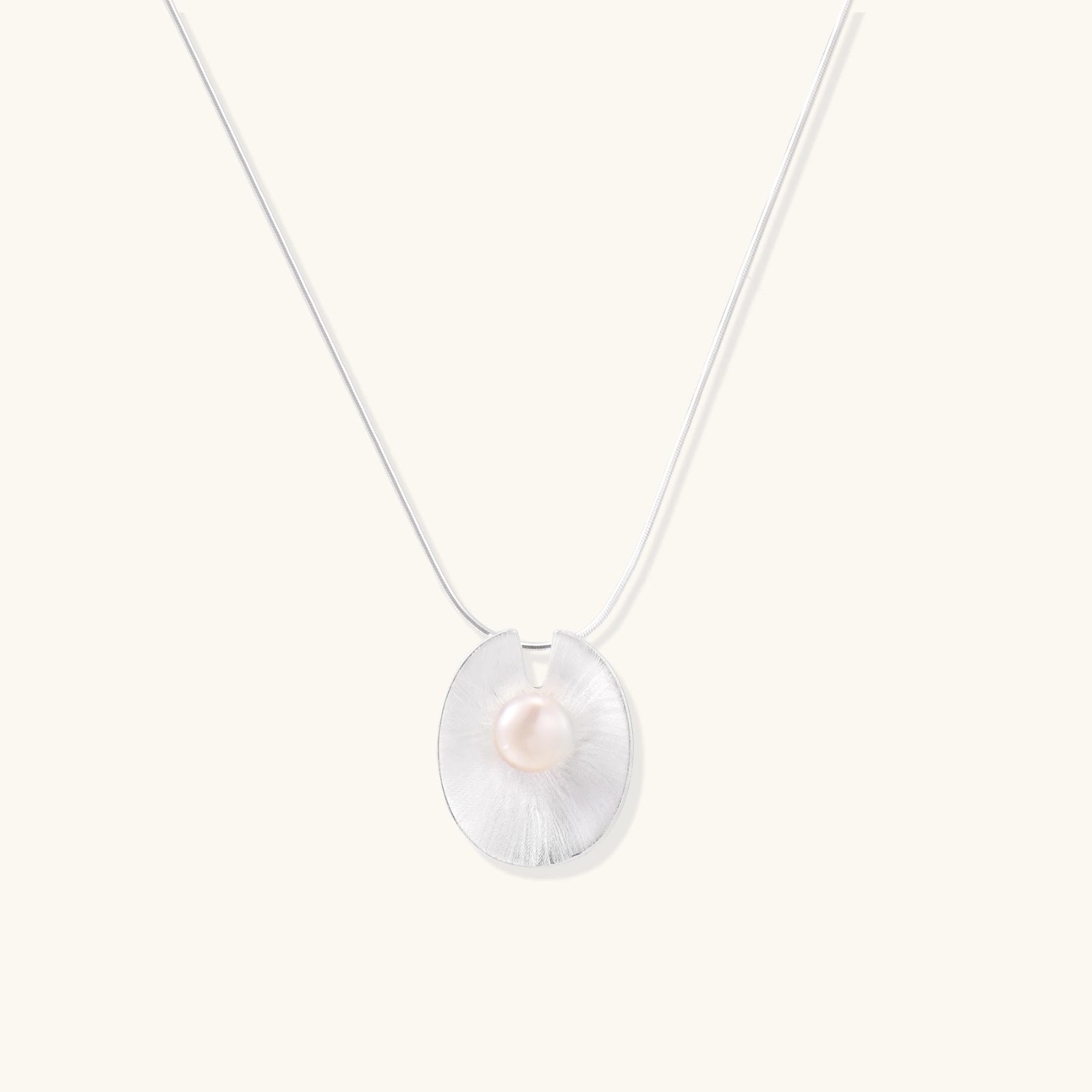 Sterling silver disc necklace with textured finish and centered freshwater pearl on delicate chain