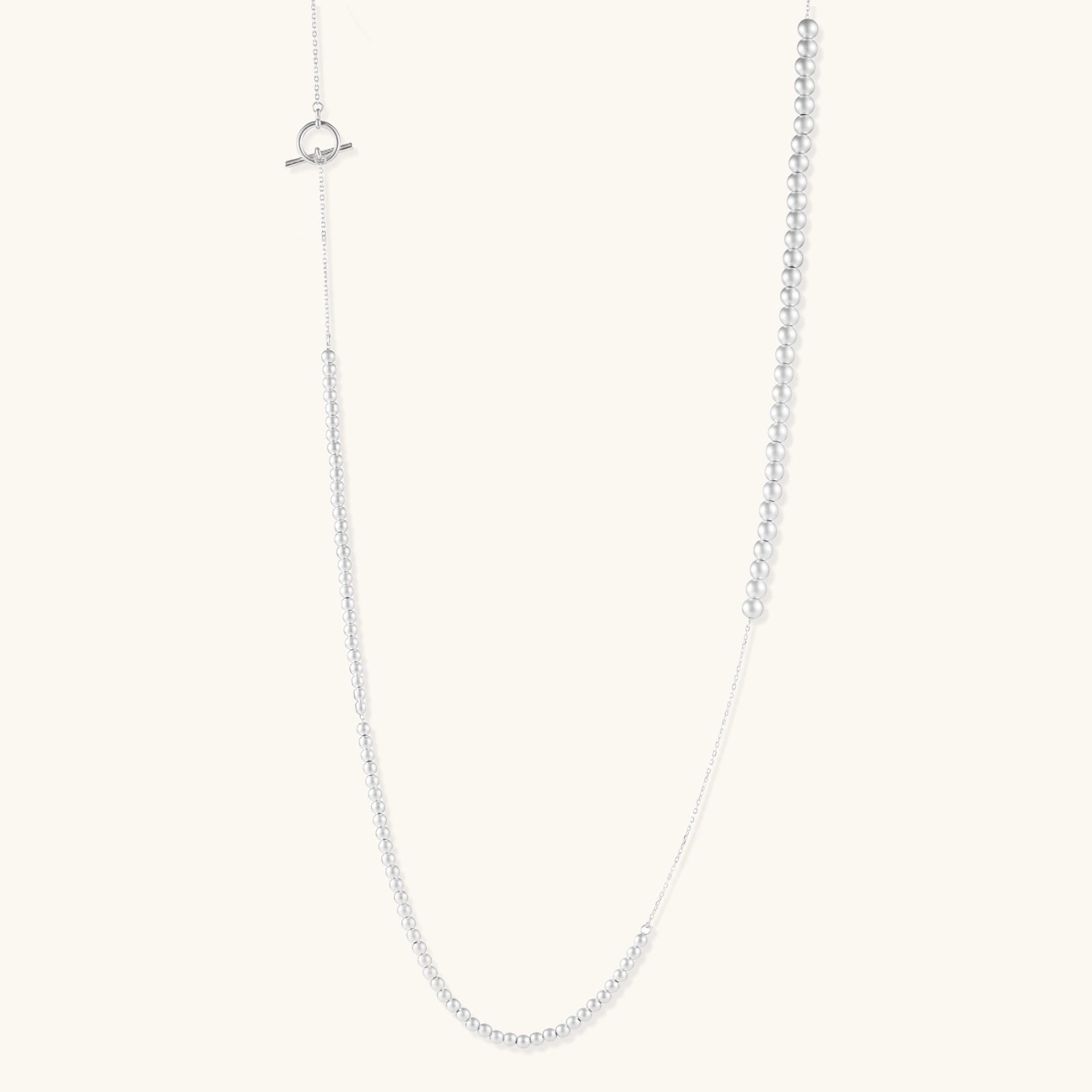 Long sterling silver beaded necklace with graduated sphere design, toggle clasp, and delicate chain extension on white background
