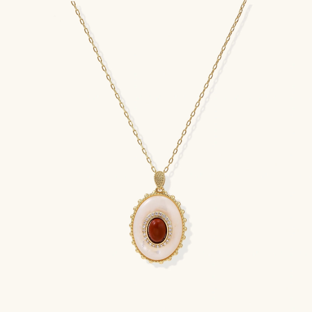 Gold pendant with oval mother-of-pearl frame, amber stone center, and crystal halo on delicate chain