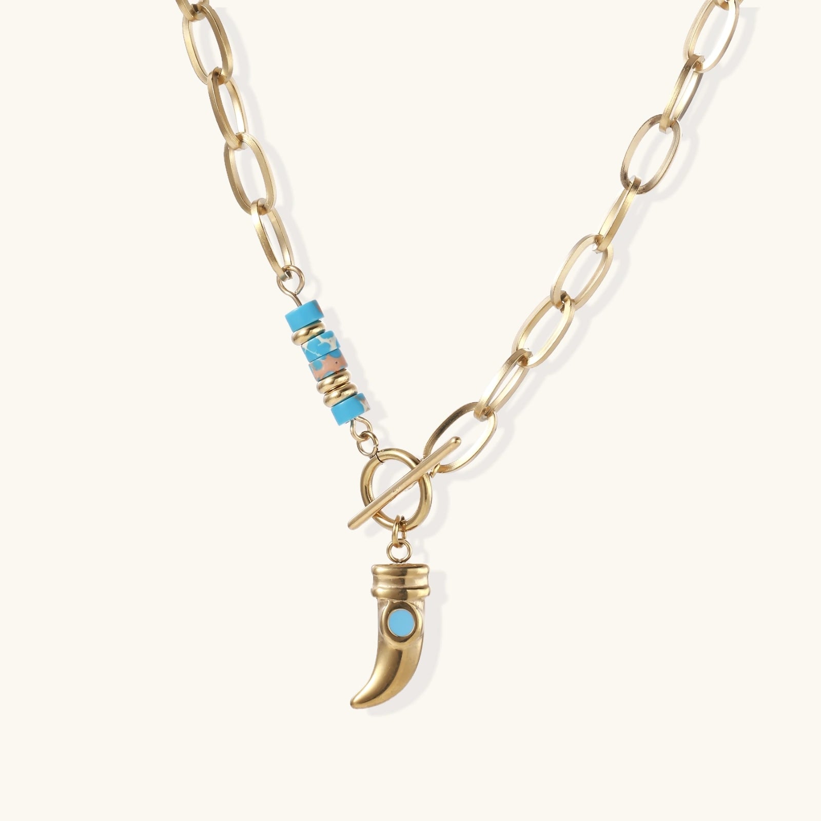 Gold chunky chain necklace with turquoise beaded accent and horn pendant on white background