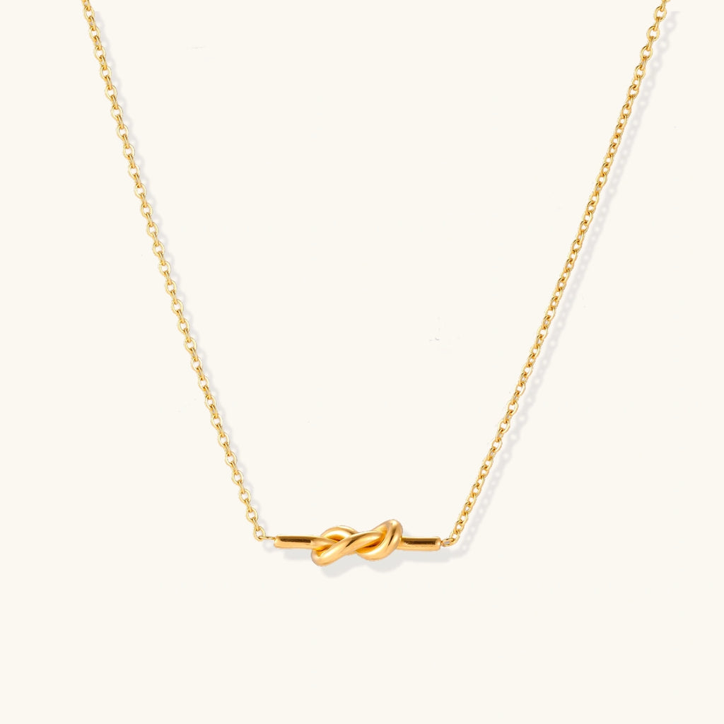 Dainty 18K gold plated necklace with infinity knot pendant on delicate chain against white background