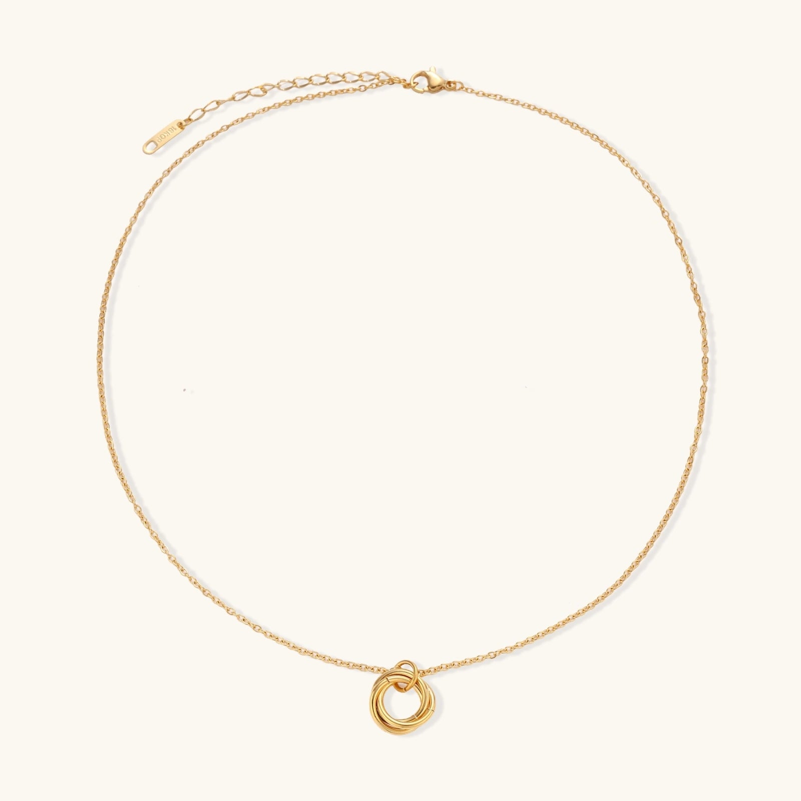 Delicate gold-plated necklace with three interlocking circle rings forming a minimalist knot pendant on cream background