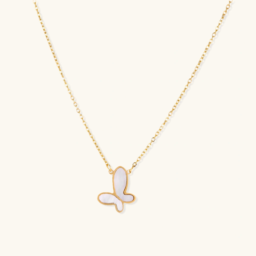 Gold-plated butterfly pendant with iridescent mother of pearl inlay on delicate chain against cream background.