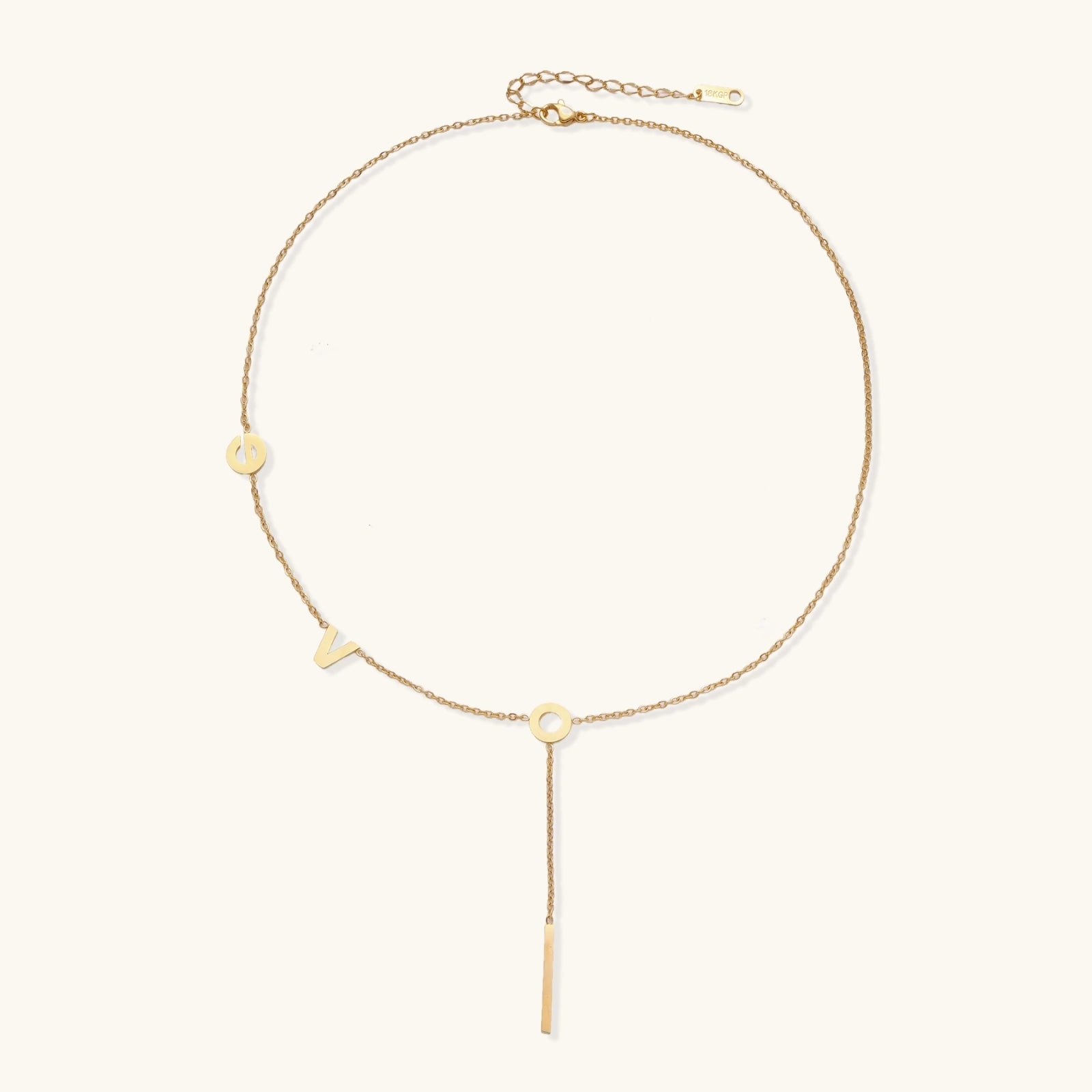 Gold Y-shaped necklace with L-O-V-E letter charms and vertical bar pendant on delicate chain against cream background