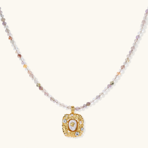 Ornate gold-plated pendant necklace with multicolored gemstone beads in purple, pink and clear tones on white background
